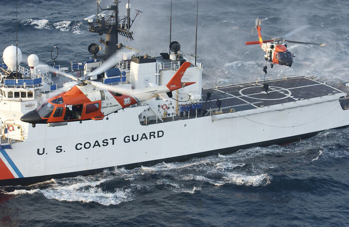 U.S. Coast Guard ship with helicopters in flight showcasing redesigned aesthetic features on the vessel.
