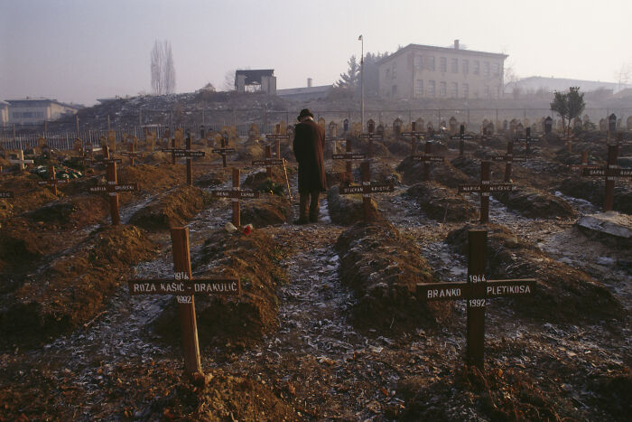 Graveyard scene with wooden crosses and a person standing, related to investigation of human safari trips and tourists paying large sums.