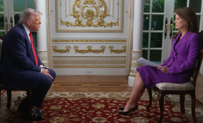 Donald Trump in a navy suit and red tie during an interview about pardoning a crypto king linked to his sons.
