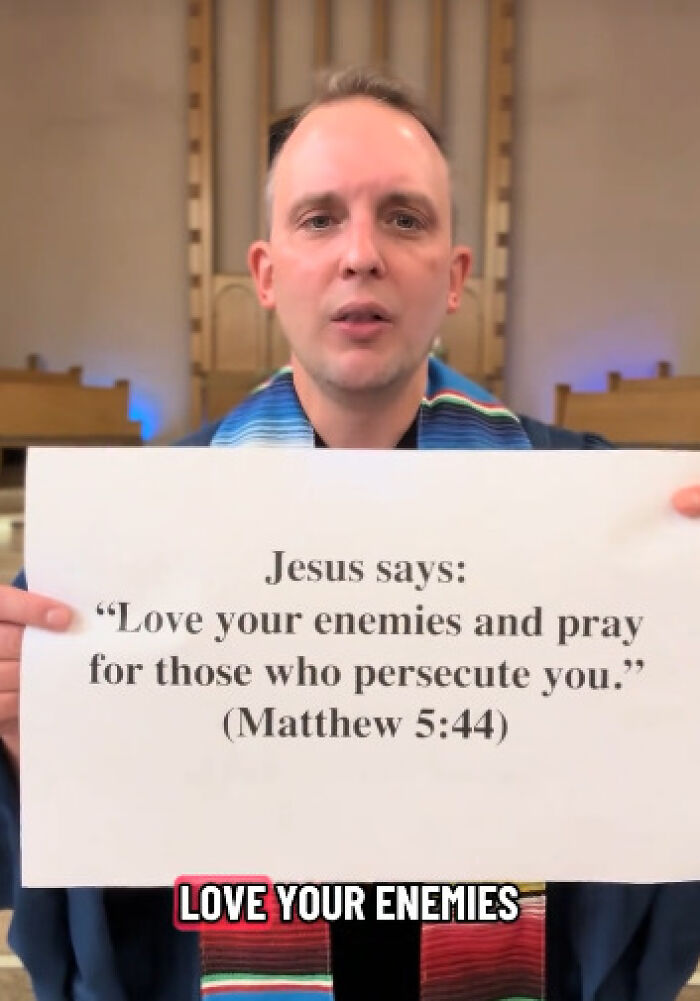 Reverend holding Bible verse sign, using scripture to oppose conservatives, sharing anti-MAGA message in church setting.