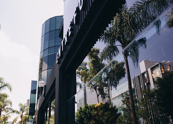 Modern building with reflective glass and palm trees, associated with the new substance Coco Chanel linked to musician slayings.