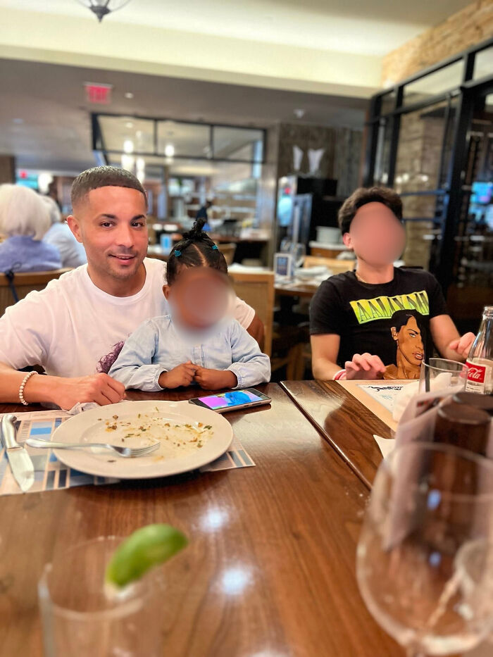 Navy sailor with son and another child sitting at a restaurant table after sharing a heartfelt moment.
