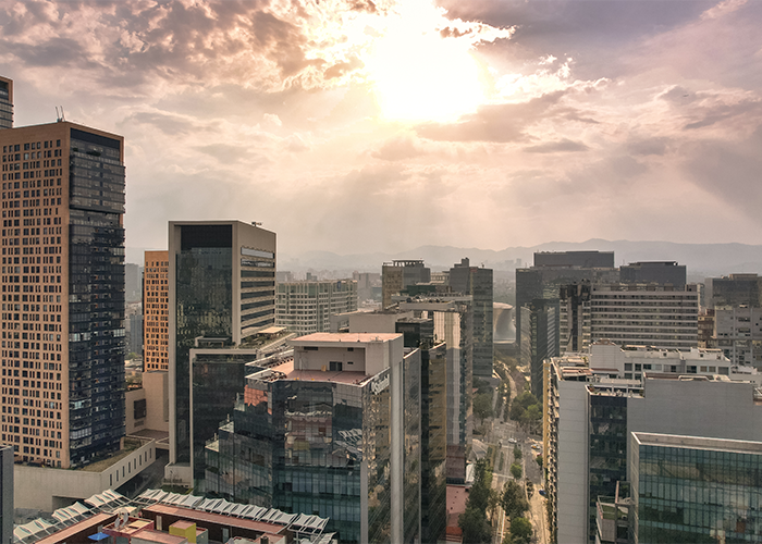 City skyline at sunset with sunlight breaking through clouds, symbolizing the rise of Coco Chanel substance linked to Colombian musicians' deaths.