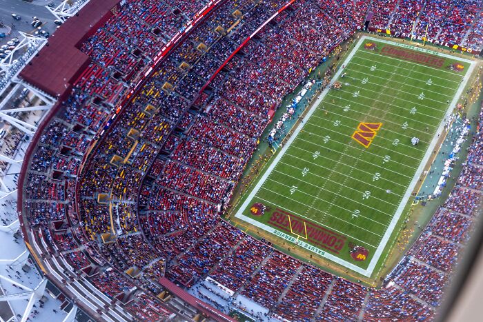 Aerial view of a packed football stadium with fans reacting to Trump&rsquo;s call to rename the stadium after him.