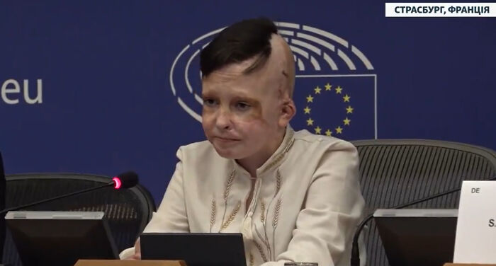 Ukrainian boy giving heartbreaking testimony at European Parliament, interpreter visibly moved and in tears during speech.