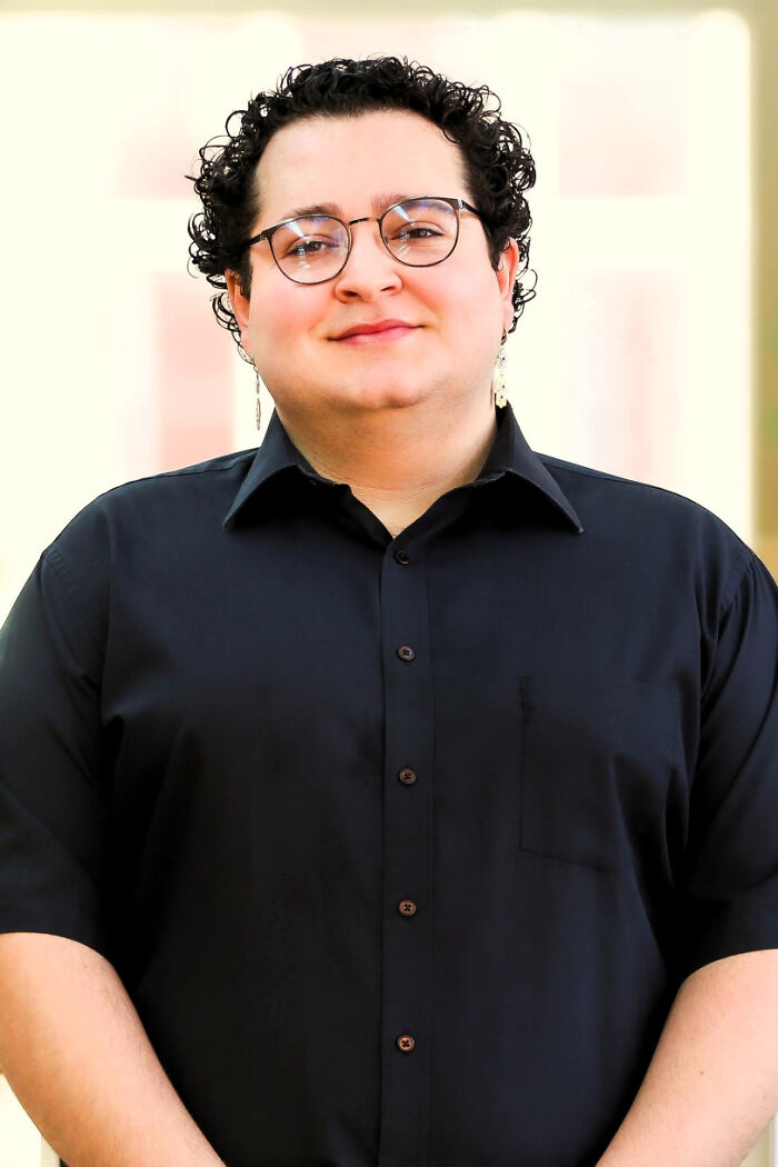 Person with curly hair and glasses wearing a black shirt, representing Brown University scrubs student profile.