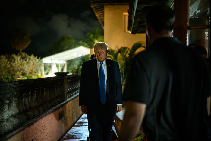 Donald Trump walking outside at night with a serious expression amid ongoing insults against female reporters.