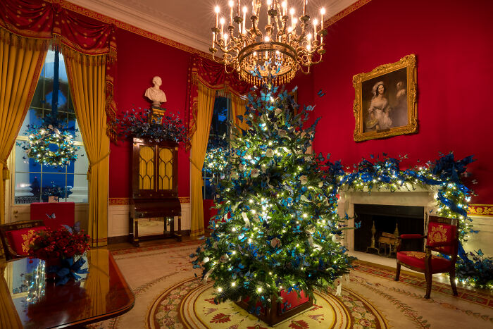 Christmas tree and blue floral decorations in a red room showcasing Melania Trump&rsquo;s 2025 Christmas decorations style.