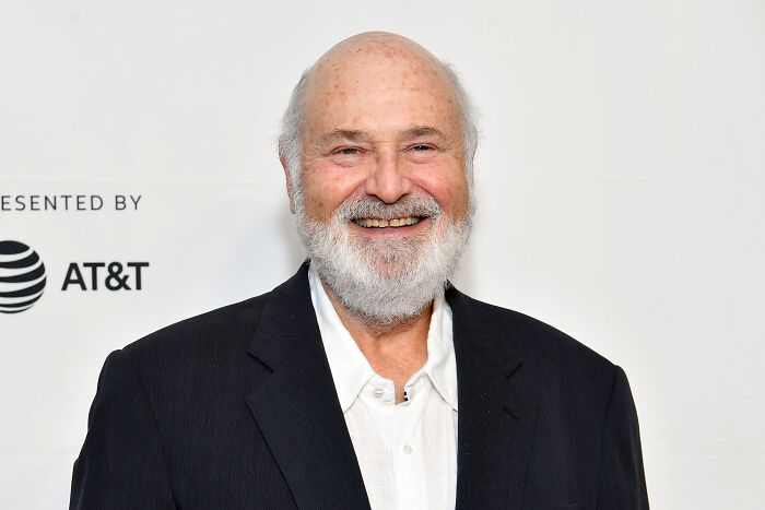 Rob Reiner smiling at an event, wearing a black blazer and white shirt, known for championing progressive causes.