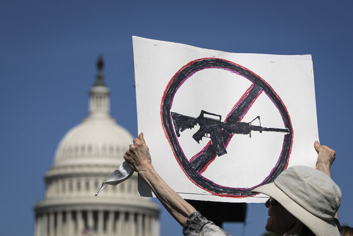 Protester holding an anti-gun sign in front of the U.S. Capitol symbolizing gun laws debate.