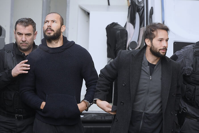 Two men in handcuffs escorted by police officers, related to an influencer accused of human trafficking allegations.