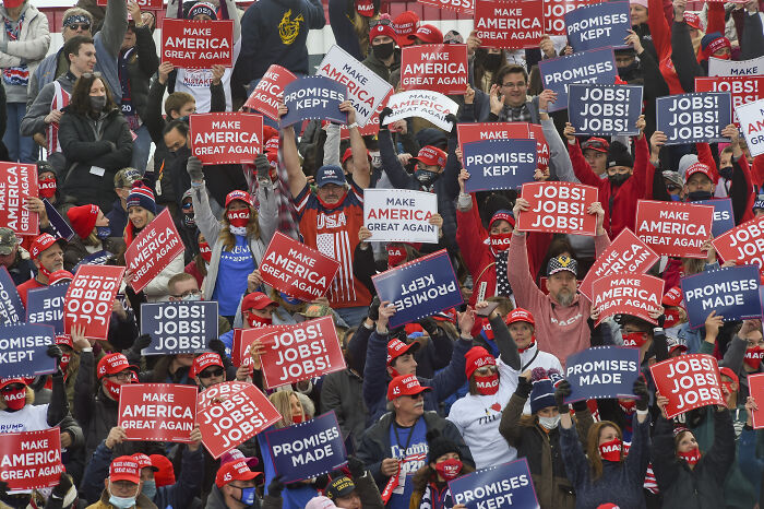 Large crowd of MAGA voters holding signs about jobs and promises at a rally amid 2024 grocery price complaint discussion.