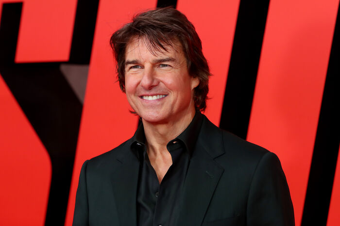 Tom Cruise smiling at a red carpet event, dressed in a black suit, linked to his epic space movie decision.