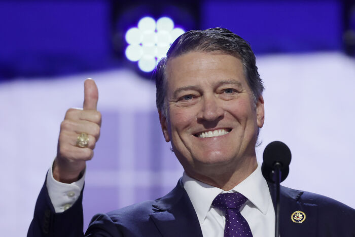 Man in suit giving thumbs up and smiling during a speech, related to Trump White House doctor health comparison.