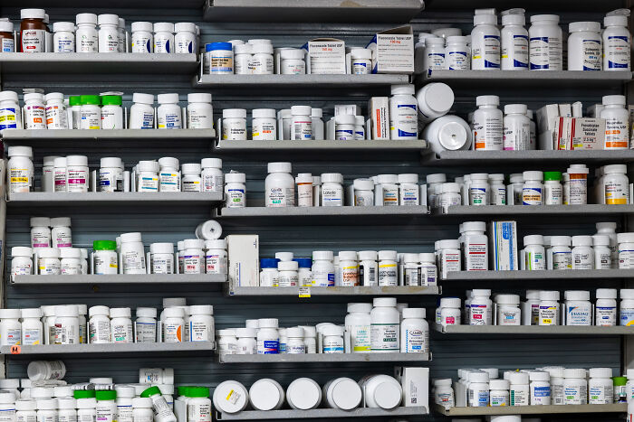 Rows of prescription medication bottles and containers on pharmacy shelves, symbolizing claims and controversies from Trump.