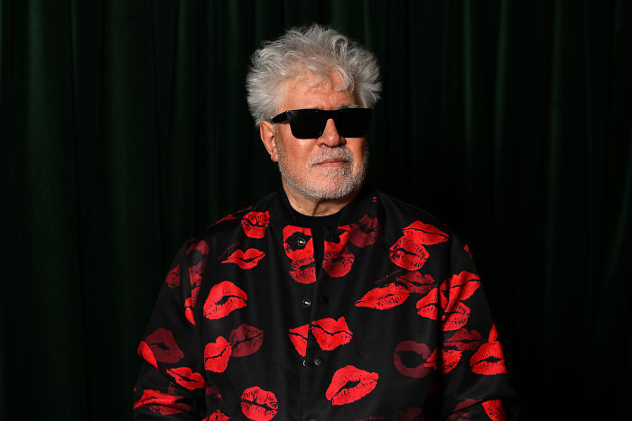 Man with white hair and black sunglasses wearing a black shirt with red lips pattern, related to celebrities slamming Donald Trump in 2025.