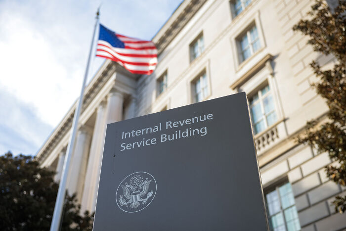 Sign for Internal Revenue Service building outside a government office with an American flag, related to IRS agents and tax on tips.
