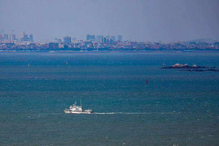 Coast guard boat patrolling open waters near a distant city skyline amid escalating tensions before WW3 in 2025.