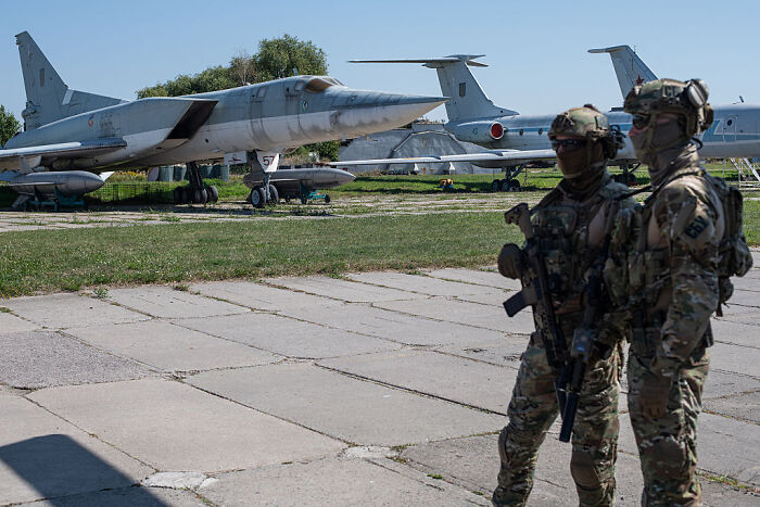 Two soldiers stand armed near military jets at an airfield related to hungover Russians impacting Ukraine&rsquo;s deep strike plan.