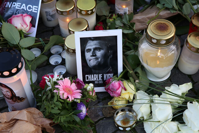 Memorial candles and flowers arranged around a photo in tribute, representing events that shook the world in 2025.