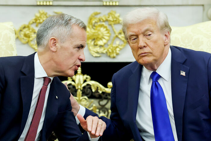Donald Trump in a dark suit and blue tie speaking seriously with a world leader during a formal meeting on diplomacy.
