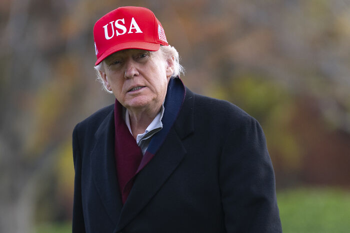 Former President Trump wearing a red USA hat outdoors, related to White House revealing reason behind Trump&rsquo;s MRI scan.