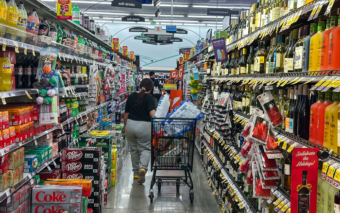 Shopper in grocery aisle with filled cart, highlighting 2024 vs 2025 grocery price complaint and viral MAGA voter reactions.