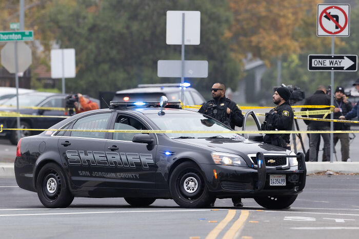 San Joaquin County sheriff officers blocking a street with police tape during manhunt for California gunman.