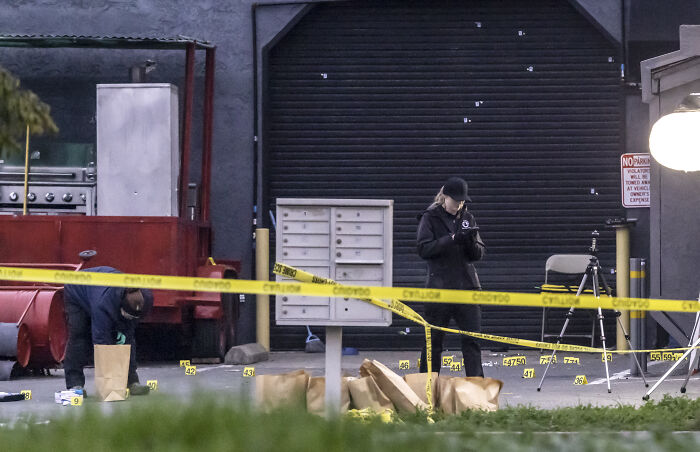 Crime scene investigators working amid evidence markers and yellow tape during California gunman manhunt after children k****d.
