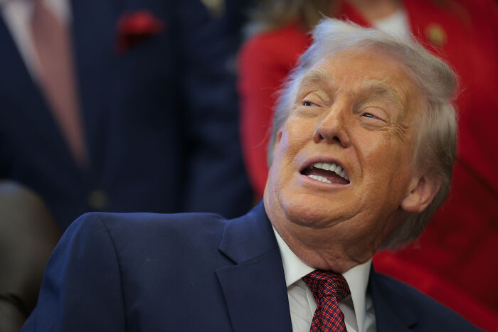 Donald Trump in a navy suit and red tie, speaking at an event related to his name added to U.S. Institute of Peace.