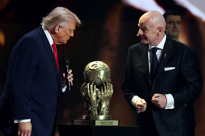 Donald Trump and Gianni Infantino near FIFA Peace Prize trophy during an award ceremony on stage.
