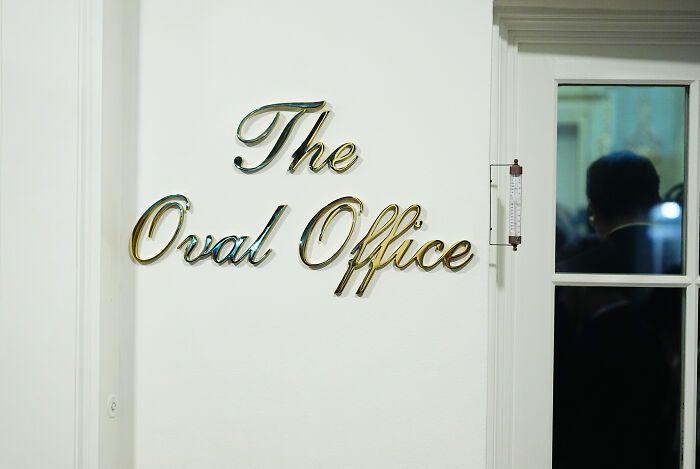 The Oval Office sign on a white wall highlighting the White House cheap tacky hotel update amid renovations.