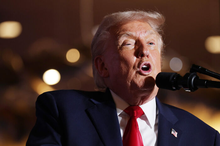 Donald Trump speaking into a microphone during an event, related to war crimes in the Caribbean discussion by experts.
