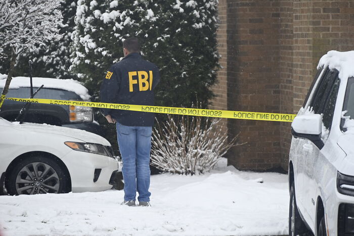 FBI agent at a snowy crime scene with police tape, linked to Brown University scrubs student profile investigation.