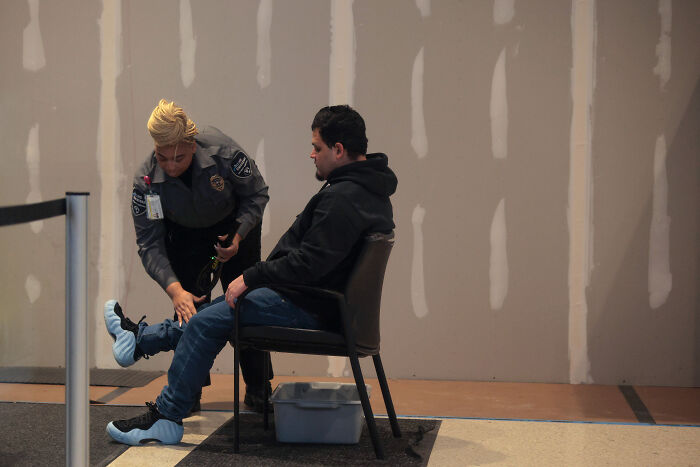 Kilmar Abrego Garcia seated while security officer fits protective shoe covers during public appearance after release