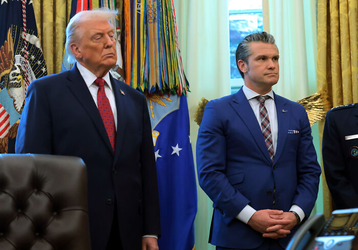 Former U.S. President and officials standing in a room with military flags, related to U.S. military d**g boat strikes.