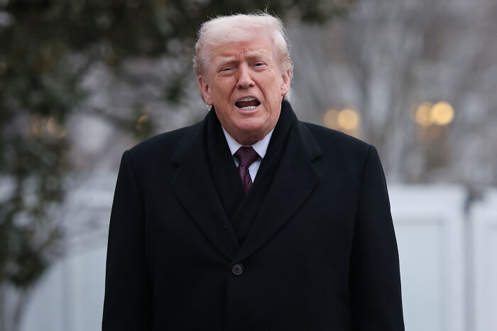 Former President Trump outdoors in a black coat, related to Kennedy Center board vote on Trump rename controversy.