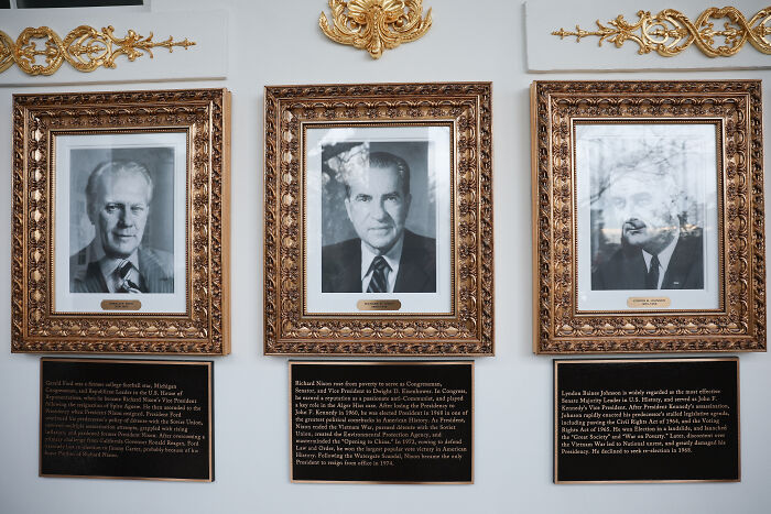 Portraits in ornate frames with plaques beneath, showing historical figures highlighted by White House display additions.