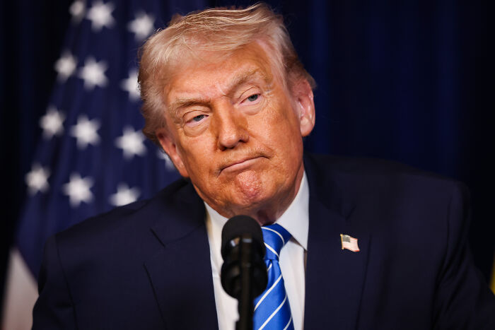 Donald Trump speaking at a podium with a US flag in the background, relating to Kennedy attacks news.