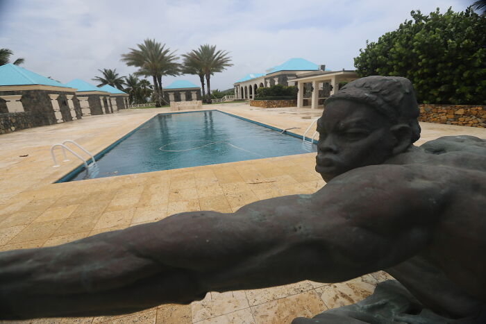 Bronze statue by a pool with palm trees on a private island, linked to Democrats teasing Epstein bank records dump.