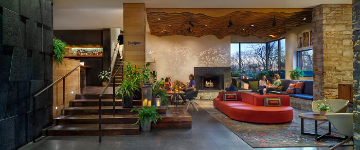 Luxurious hotel lobby with modern design, red seating, indoor plants, and ambient lighting, highlighting luxury hotel spending.