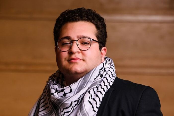 Portrait of Mustapha Kharbouch wearing glasses and patterned scarf with Brown University scrubs student profile background
