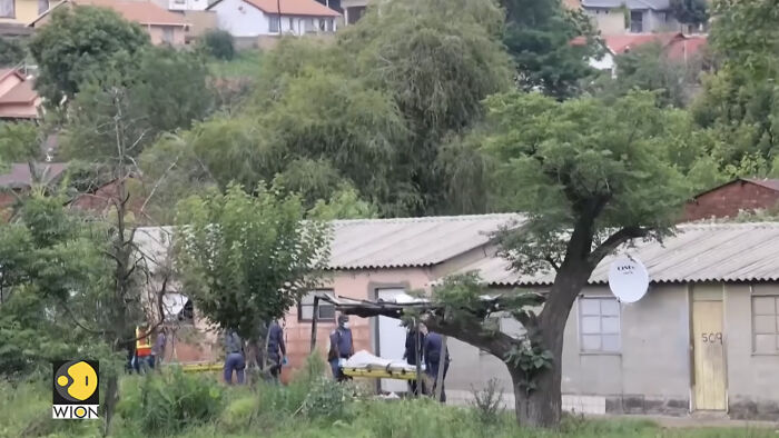 Emergency responders carrying victims on stretchers near a rural house after a fatal mass shooting involving children and teens.