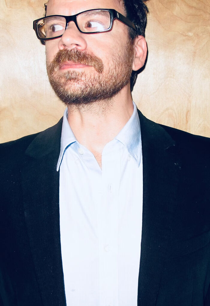 Man with glasses and beard wearing black jacket and white shirt, representing Trump&rsquo;s Kennedy Center website hijacked comedy gold.