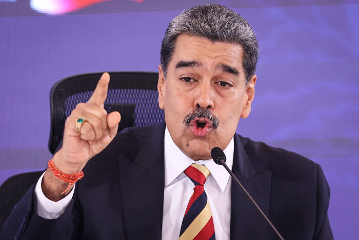 Man in suit speaking passionately at a microphone during an event related to oil tanker capture near Venezuela.