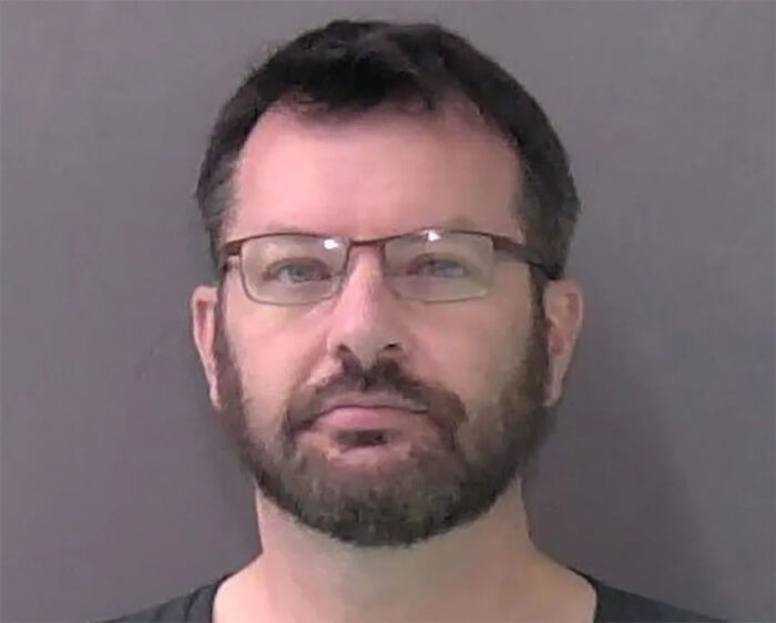 Mugshot of a man wearing glasses with a beard, related to the army gynecologist accused of secretly recording patients.