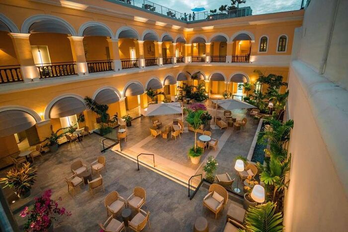 Luxury hotel courtyard in Puerto Rico with fine dining setup and tropical plants under warm lighting at dusk.