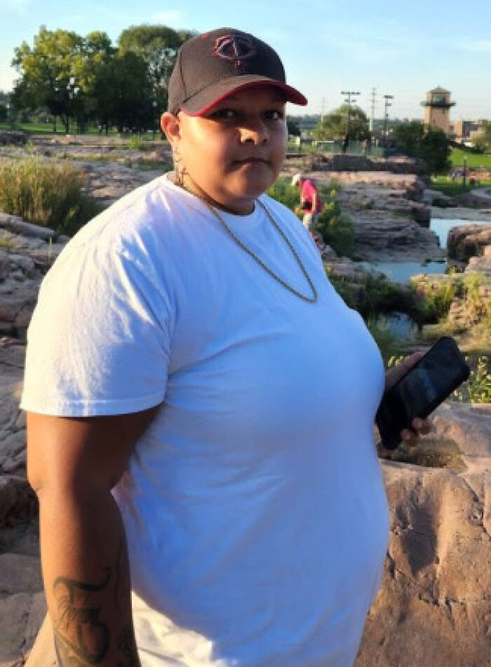 Person in a white t-shirt and black cap holding a phone outdoors near rocky terrain, related to crimes that shocked the nation.