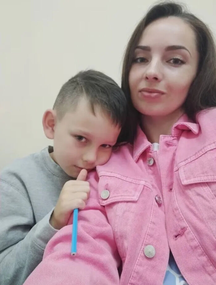 Woman in a pink jacket with a young boy leaning on her, capturing an emotional moment linked to Ukrainian testimony at European Parliament.