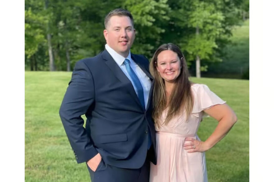 Young couple posing outdoors with trees and grass, related to deceased parents brutal attack and toddler found cuddling keywords.